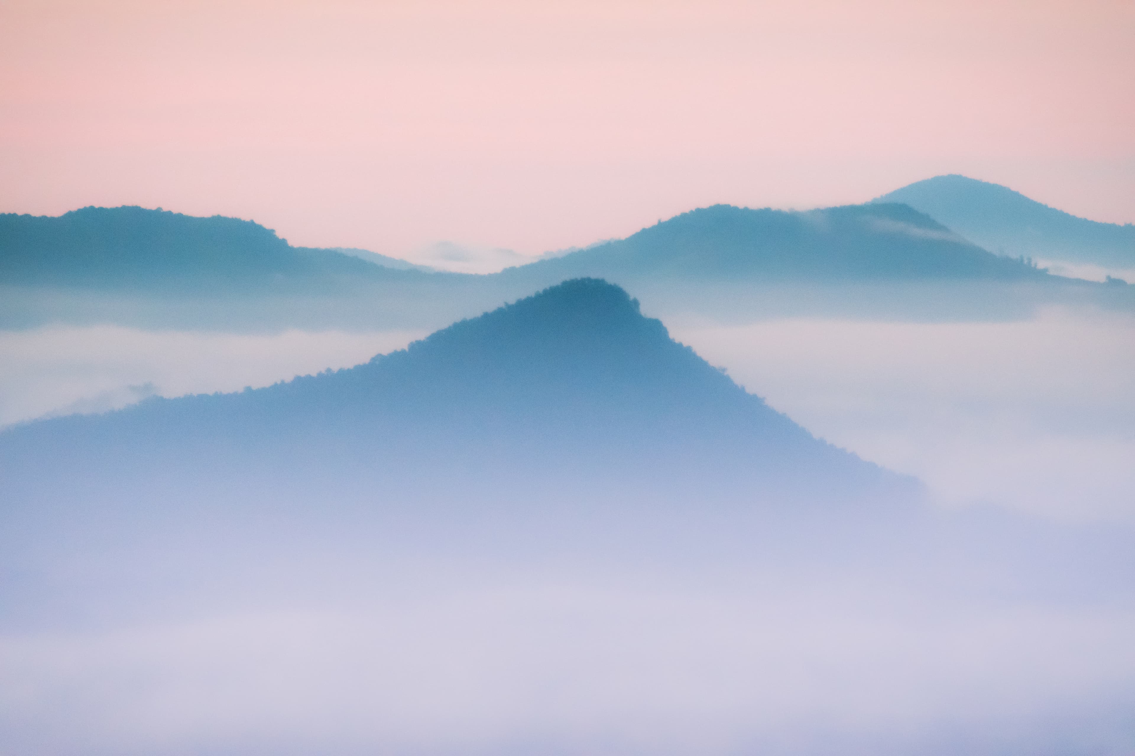 Gentle colors and fog create a minimalist mountain scene.